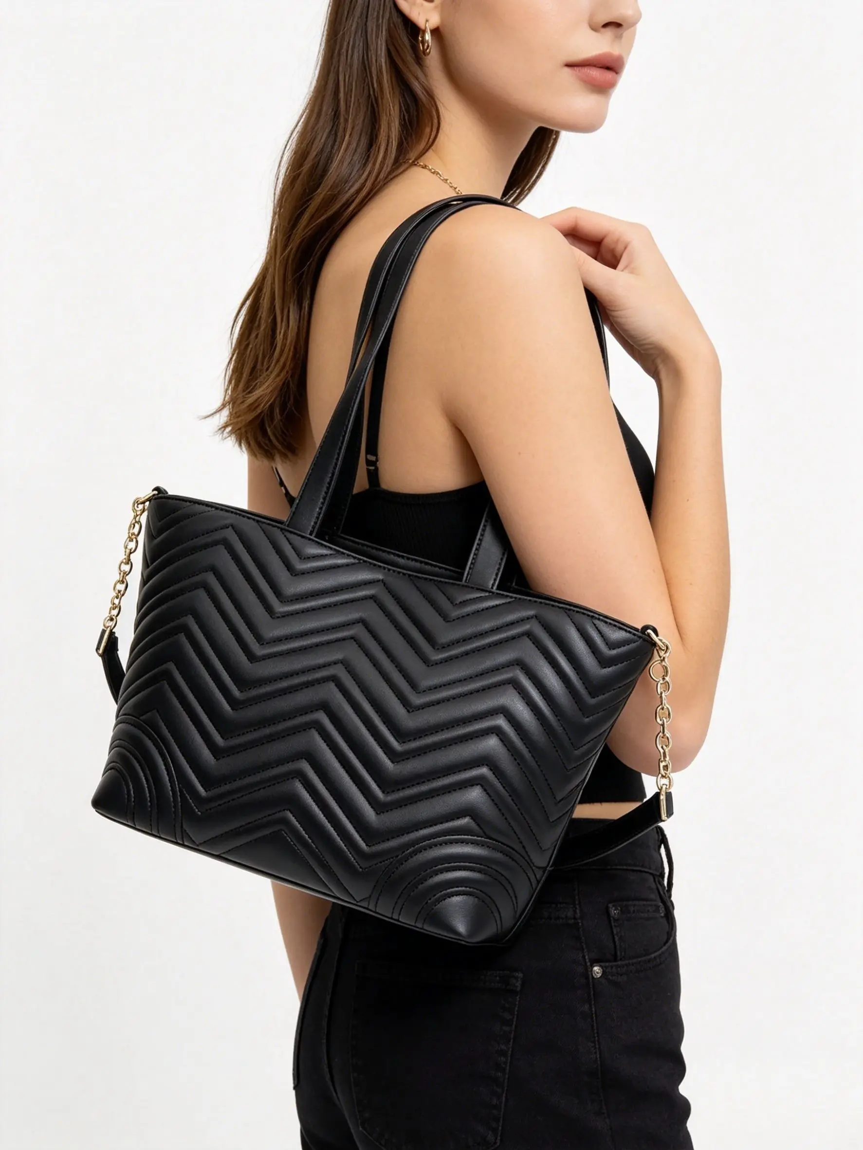 Black herringbone quilted leather handbag, with gold chain detailing, designed to be spacious.
Black herringbone quilted leather handbag, with gold chain detailing, designed to be spacious.