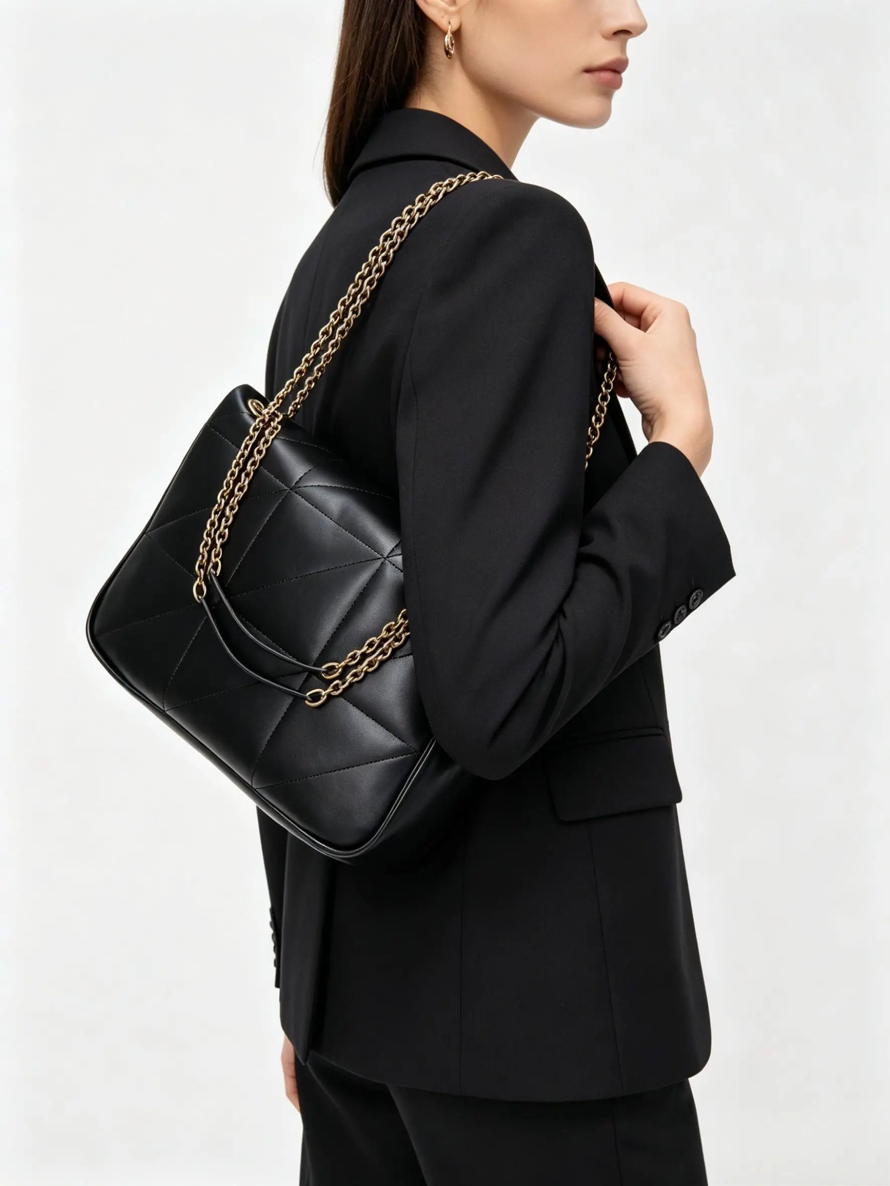Black quilted leather shoulder bag with gold-tone chain straps and a spacious, slouchy silhouette.
Black quilted leather shoulder bag with gold-tone chain straps and a spacious, slouchy silhouette.