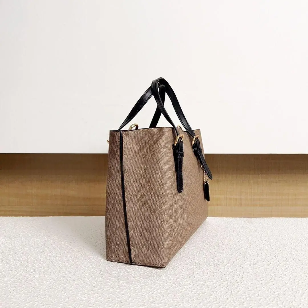 Taupe canvas and black leather structured handbag, adjustable leather handles with gold hardware, with a detachable crossbody strap.
Taupe canvas and black leather structured handbag, adjustable leather handles with gold hardware, with a detachable crossbody strap.