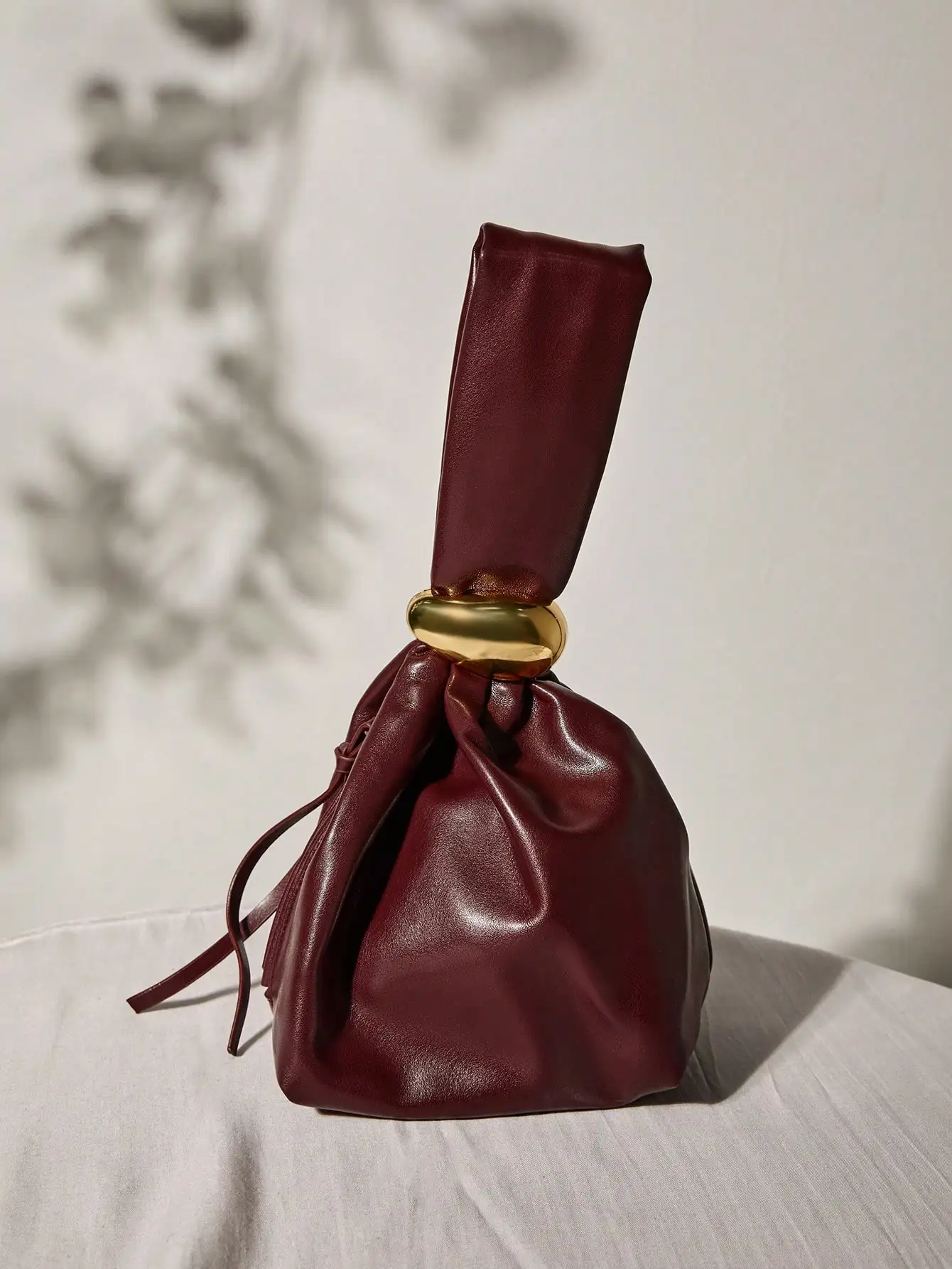 Вечерняя сумка-ведро из бордовой искусственной кожи на шнурке с золотой ручкой-кольцом
Вечерняя сумка-ведро из бордовой искусственной кожи на шнурке с золотой ручкой-кольцом
