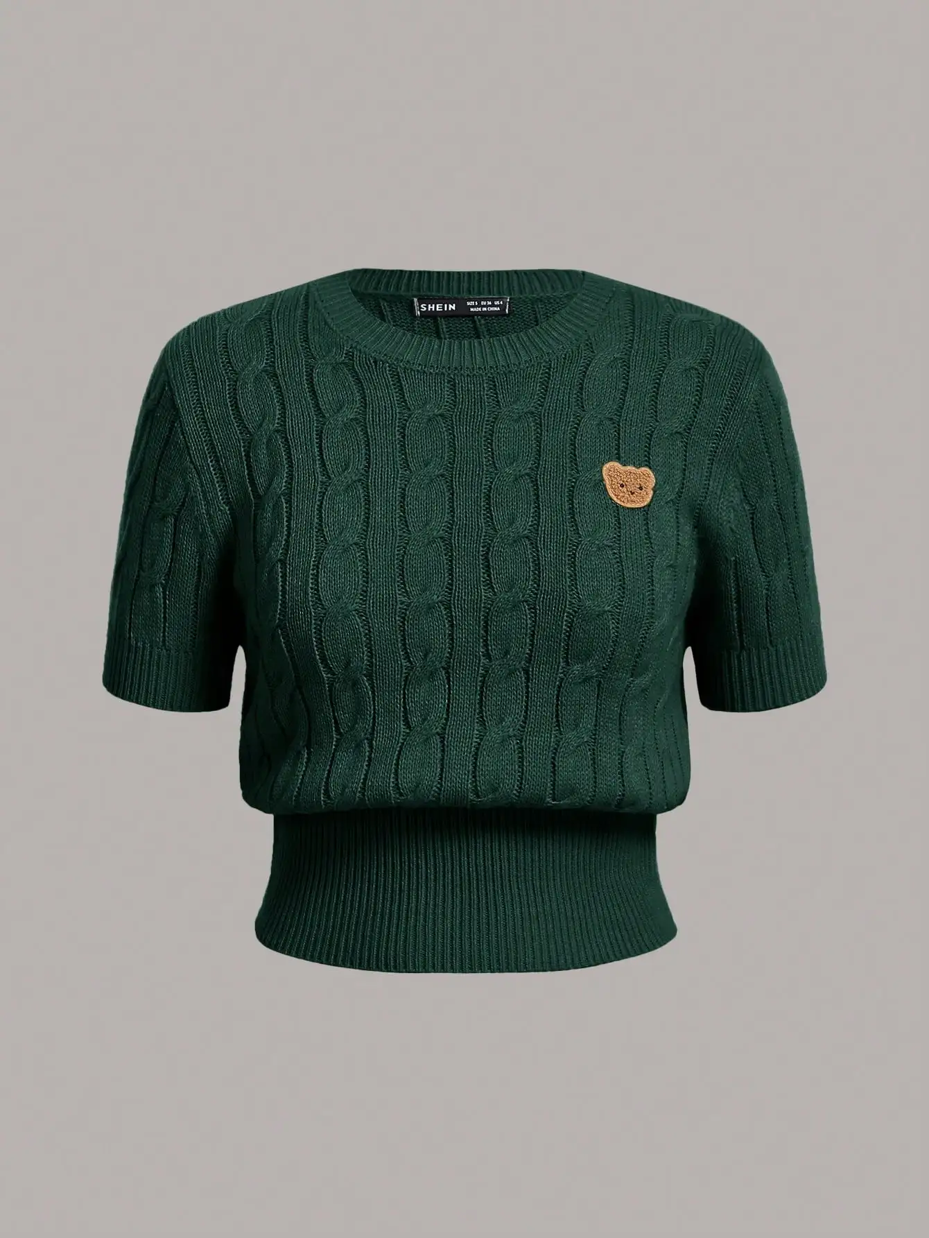 Зеленый укороченный топ с короткими рукавами и вязаным узором и нашивкой в виде медведя
Зеленый укороченный топ с короткими рукавами и вязаным узором и нашивкой в виде медведя