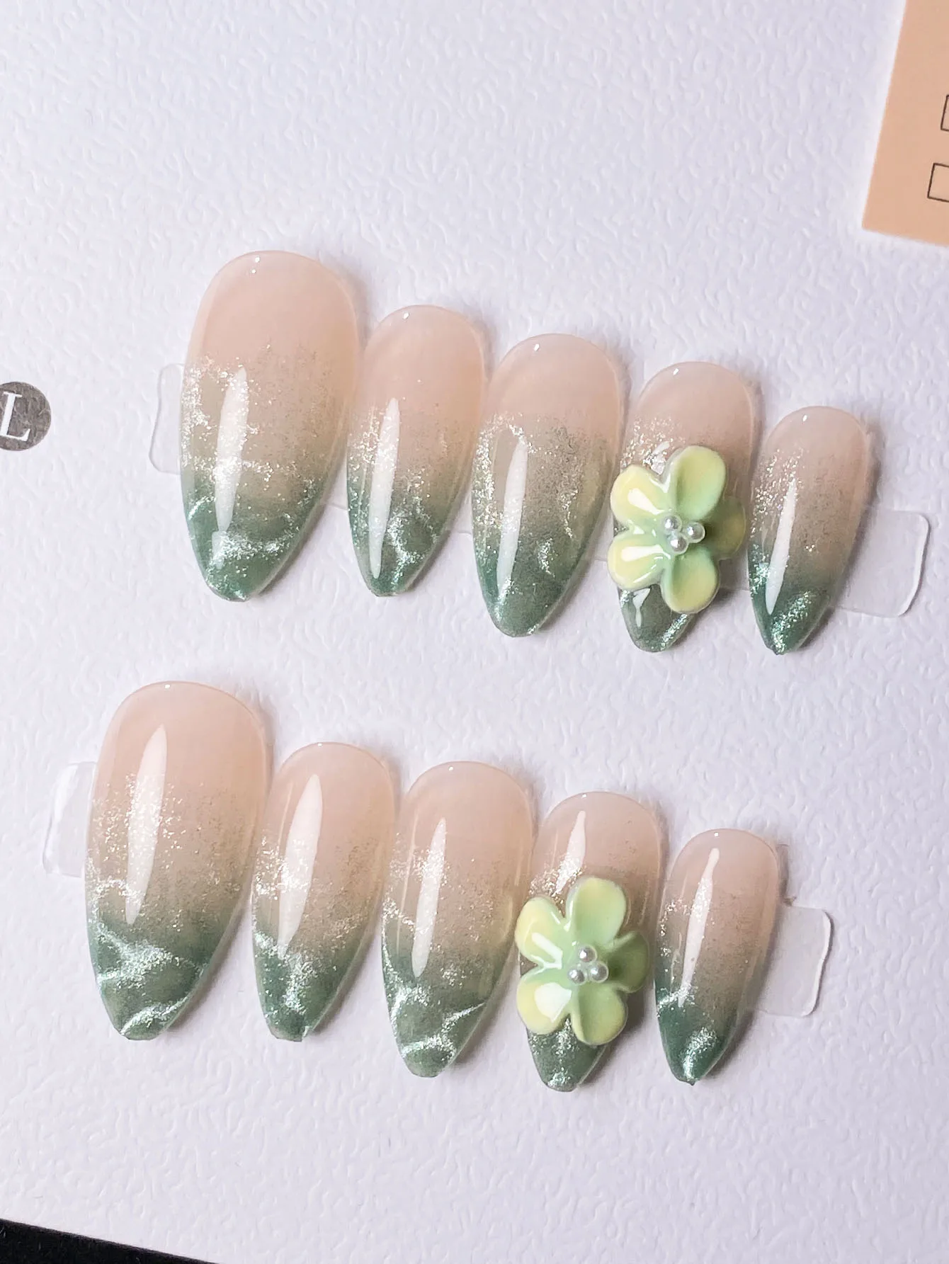 10 handmade almond-shaped nail tips in blue-green cat-eye gradient with pressed flower ocean design and a high-end finish.
10 handmade almond-shaped nail tips in blue-green cat-eye gradient with pressed flower ocean design and a high-end finish.