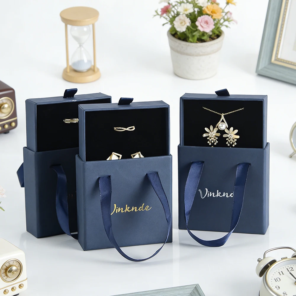Темно-синий ящик с логотипом, выдвижная упаковка для ювелирных изделий, подарочная коробка с ручкой, чехол для упаковки продуктов, портативные коробки для хранения сережек и колец
Темно-синий ящик с логотипом, выдвижная упаковка для ювелирных изделий, подарочная коробка с ручкой, чехол для упаковки продуктов, портативные коробки для хранения сережек и колец