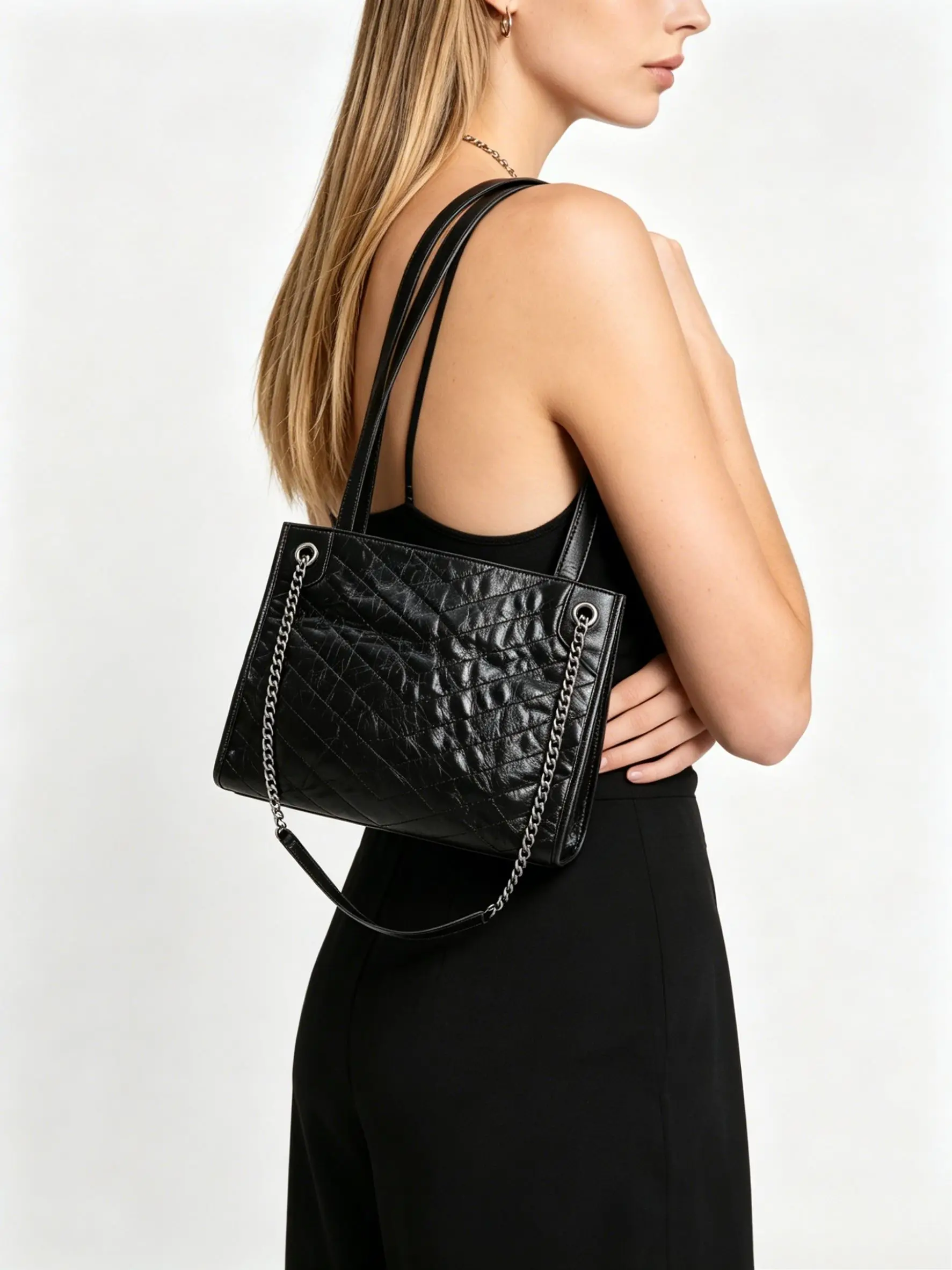 Black quilted leather tote bag with diamond stitching, silver-tone chain straps, and a slouchy, casual design.
Black quilted leather tote bag with diamond stitching, silver-tone chain straps, and a slouchy, casual design.