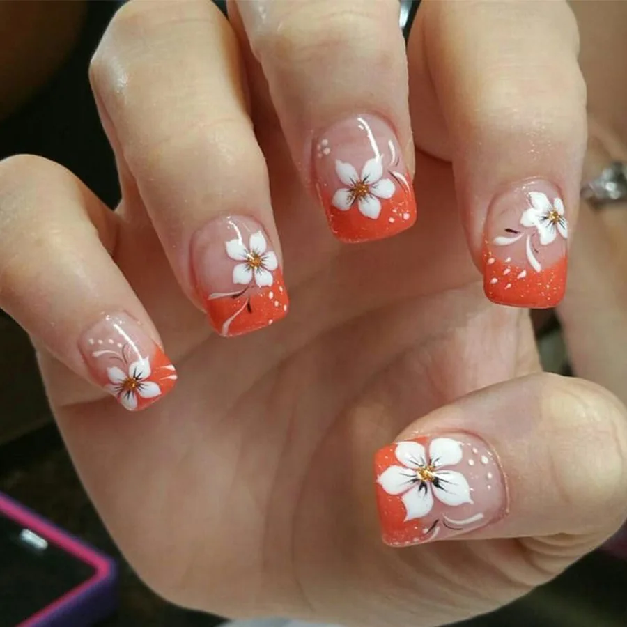 Simple short cube-shaped false nails in elegant orange and white French style with floral accents
Simple short cube-shaped false nails in elegant orange and white French style with floral accents