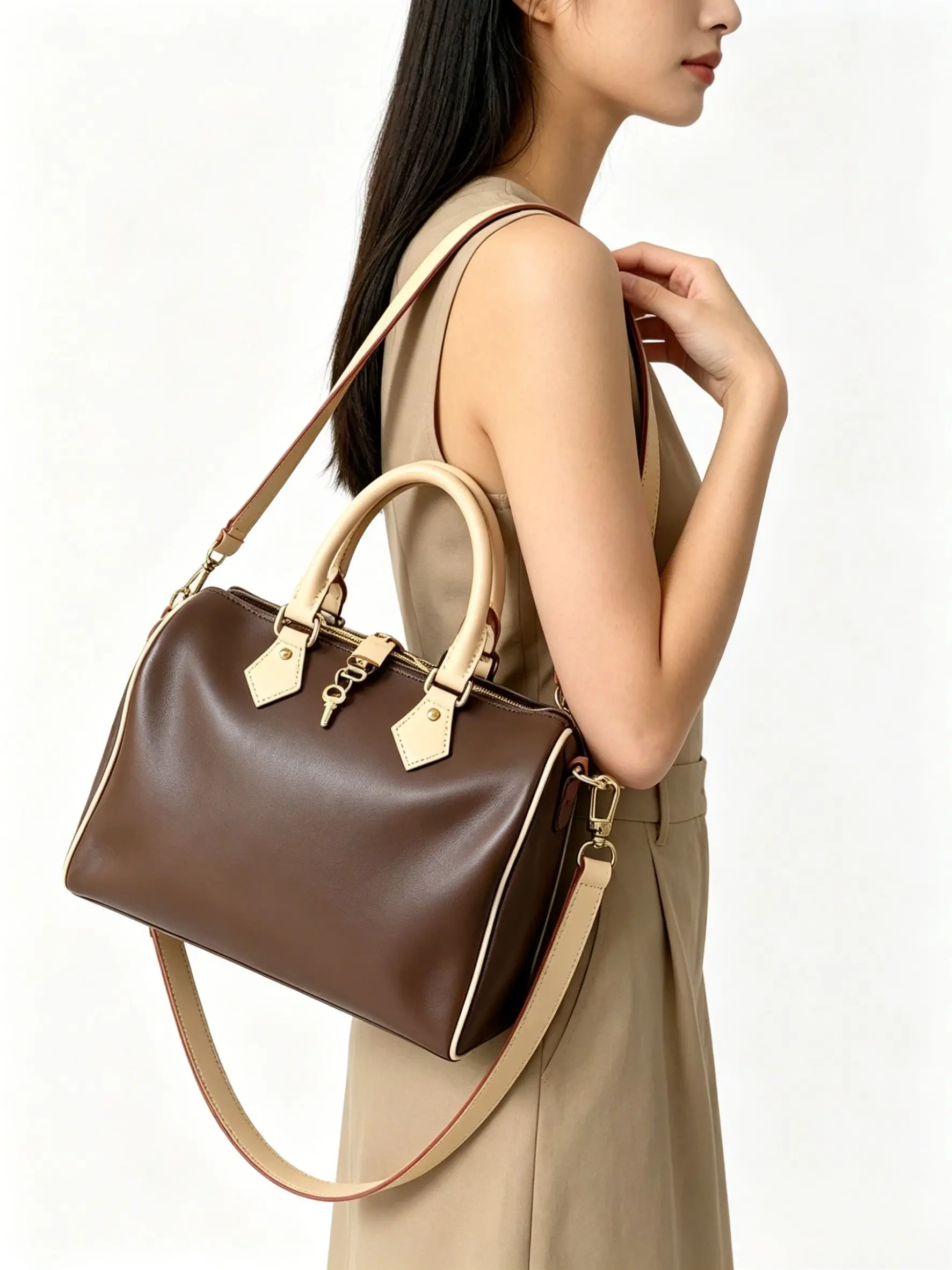 Classic barrel-style handbag crafted from smooth brown leather with beige accents, featuring top handles, a zipper closure, and a detachable adjustable strap.
Classic barrel-style handbag crafted from smooth brown leather with beige accents, featuring top handles, a zipper closure, and a detachable adjustable strap.