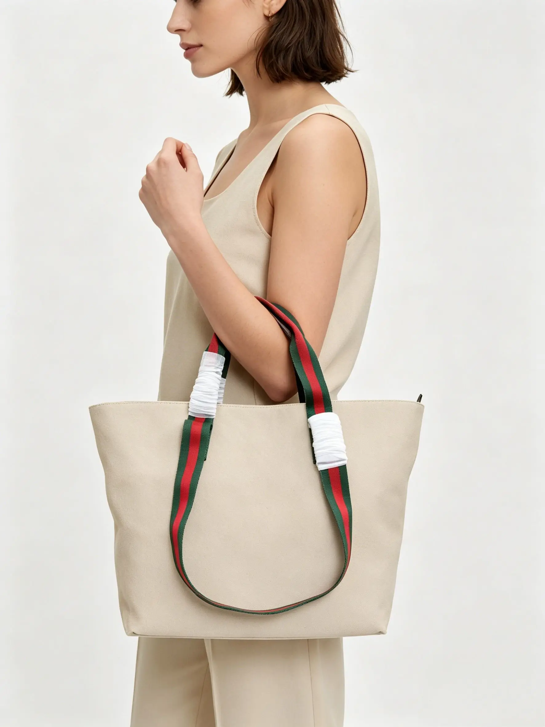 Beige genuine leather tote bag with red-green striped fabric handles and zipper closure.
Beige genuine leather tote bag with red-green striped fabric handles and zipper closure.