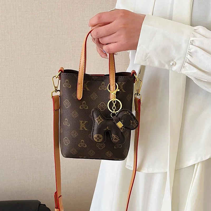 Новая модная городская простая женская сумка из искусственной кожи, маленькая сумка-ведро в стиле ретро с принтом, молодежная универсальная сумка через плечо
Новая модная городская простая женская сумка из искусственной кожи, маленькая сумка-ведро в стиле ретро с принтом, молодежная универсальная сумка через плечо