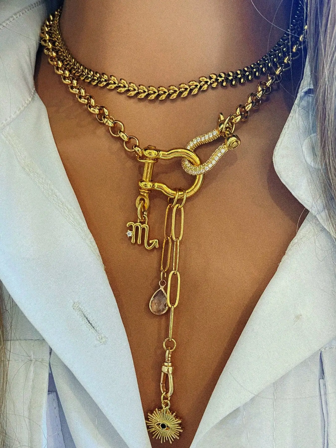 Многослойное золотистое ожерелье с цепочкой, украшенной кристаллами, с застежкой, символом знака зодиака и подвеской в виде солнечного луча.
Многослойное золотистое ожерелье с цепочкой, украшенной кристаллами, с застежкой, символом знака зодиака и подвеской в виде солнечного луча.