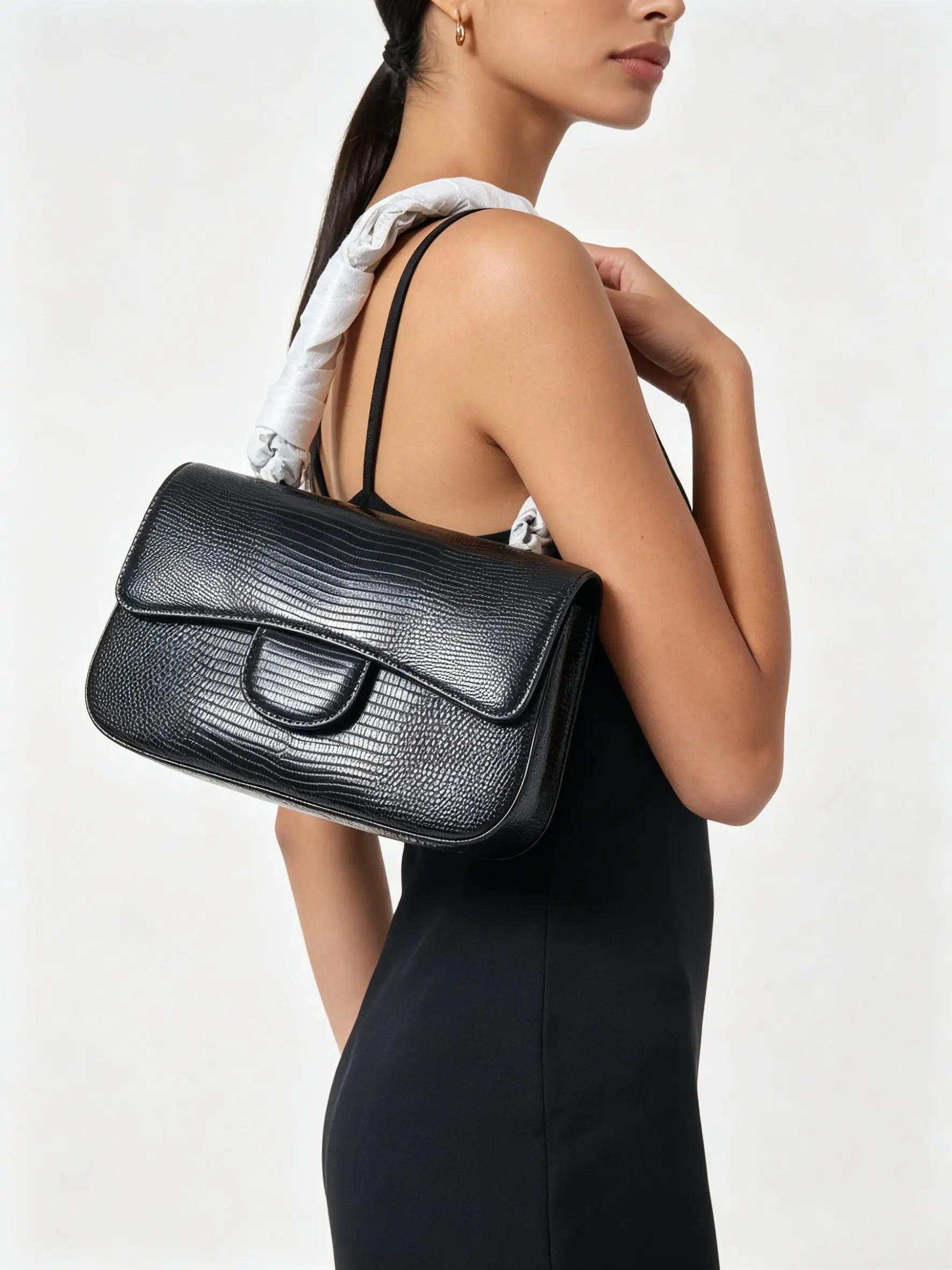 Black lizard-embossed leather shoulder bag with a silver-tone chain strap and a fold-over flap closure.
Black lizard-embossed leather shoulder bag with a silver-tone chain strap and a fold-over flap closure.