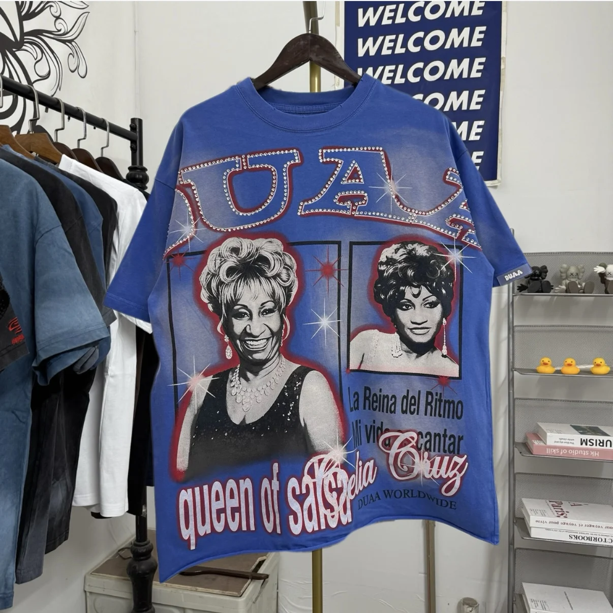 Футболка DUAA Celia Cruz в винтажном американском стиле, свободного кроя, с коротким рукавом, со стразами, с надписью «Queen of Salsa», из хлопка и полиэстера, с круглым вырезом.
Футболка DUAA Celia Cruz в винтажном американском стиле, свободного кроя, с коротким рукавом, со стразами, с надписью «Queen of Salsa», из хлопка и полиэстера, с круглым вырезом.