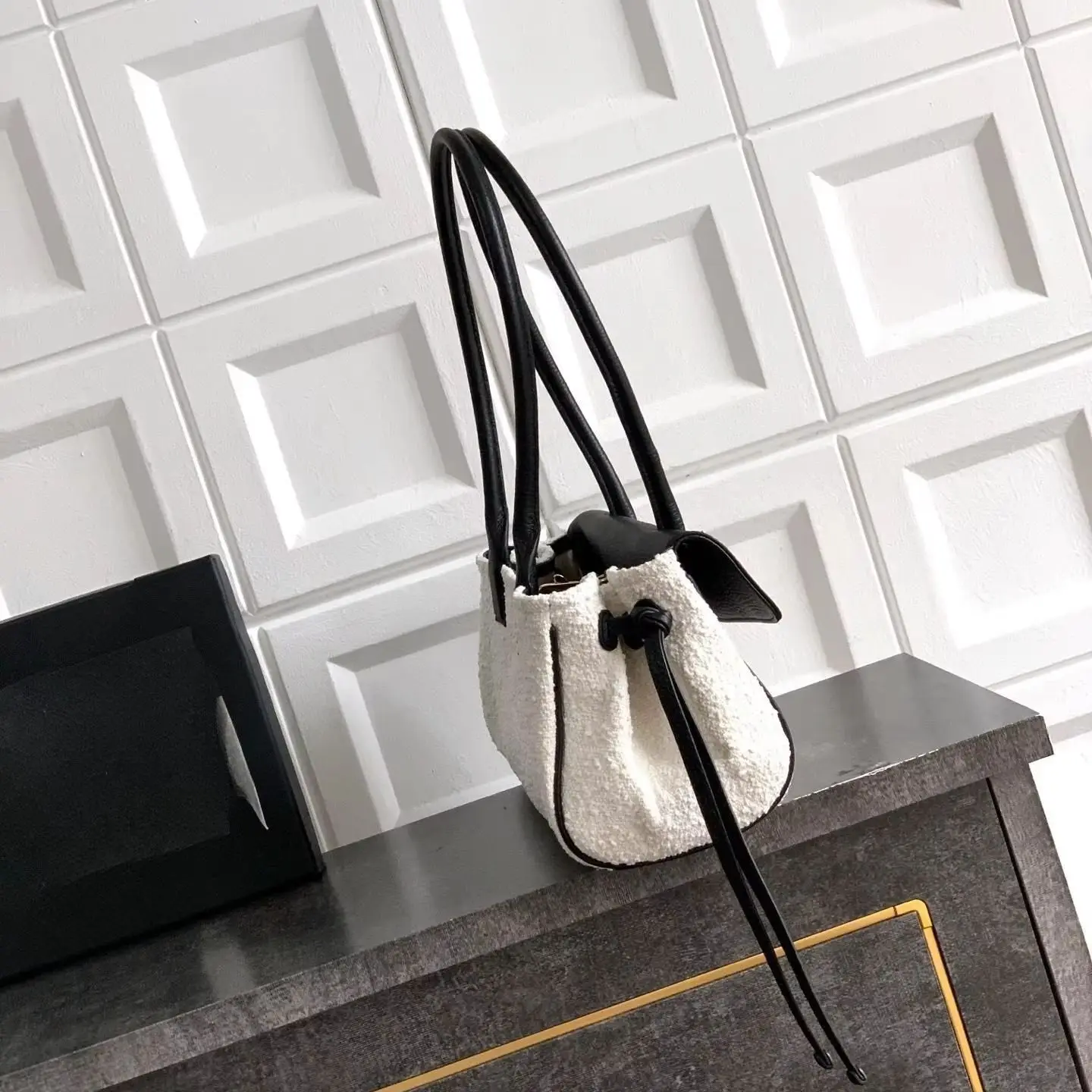 Minimalist rectangular underarm handbag, made of black thin leather, with drawstring details on the side edges and a slim horizontal shape.
Minimalist rectangular underarm handbag, made of black thin leather, with drawstring details on the side edges and a slim horizontal shape.