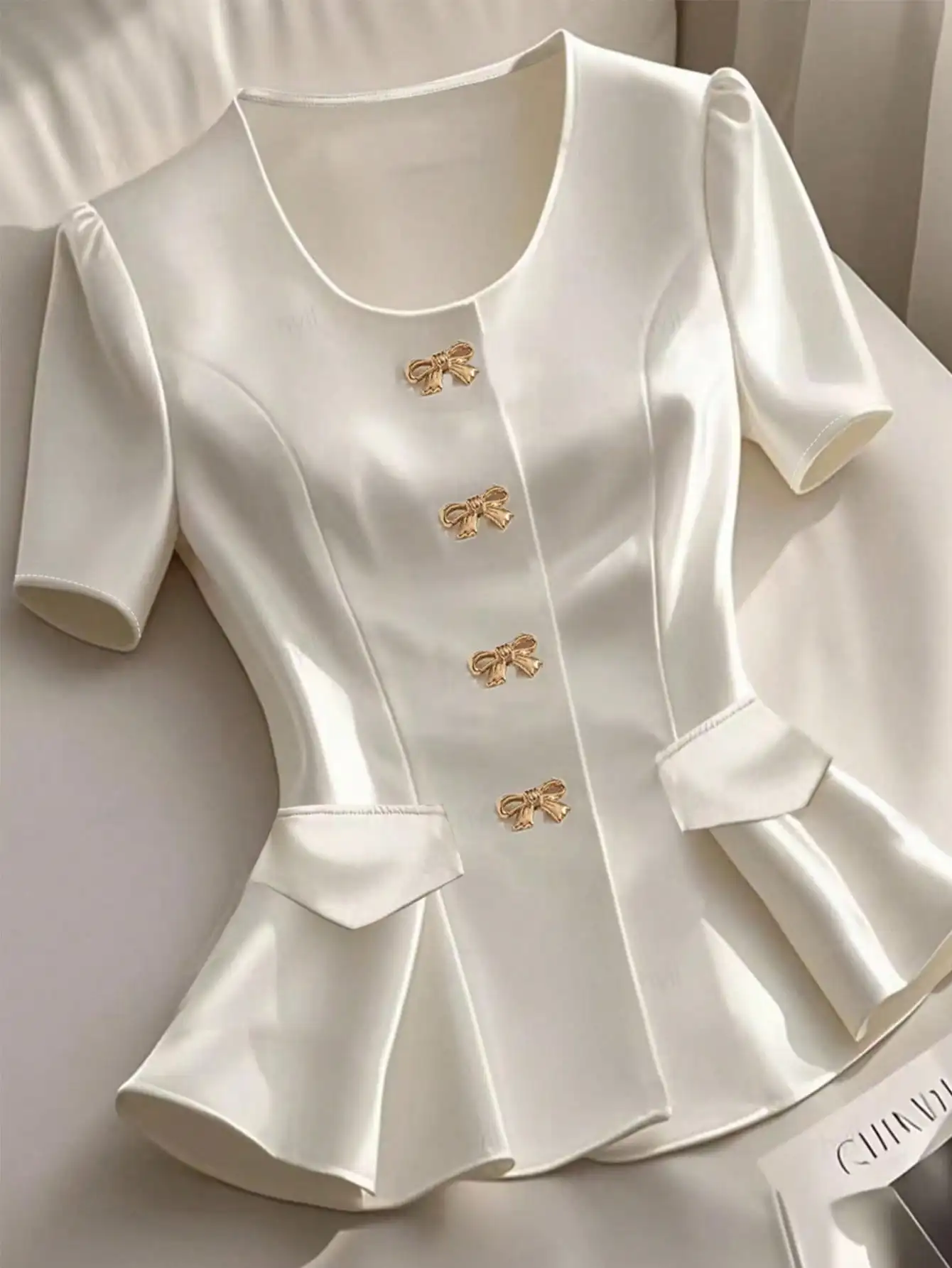 Elegant Ivory Satin Short Sleeve Blouse with Gold Bow Buttons and Peplum Hem
Elegant Ivory Satin Short Sleeve Blouse with Gold Bow Buttons and Peplum Hem