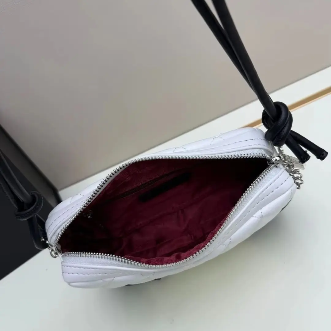 White and black two-tone quilted leather shoulder bag with diamond stitching and knotted strap details.
White and black two-tone quilted leather shoulder bag with diamond stitching and knotted strap details.