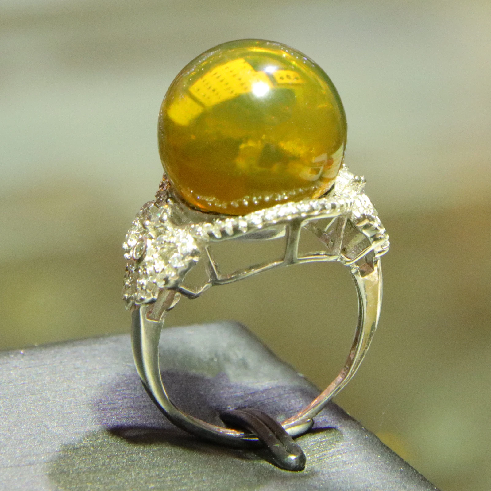 Romantic Anniversary Gift for Her: 15mm Blue Amber Ring with Lover's Bridge Setting & Sparkling Floral Halo
Romantic Anniversary Gift for Her: 15mm Blue Amber Ring with Lover's Bridge Setting & Sparkling Floral Halo