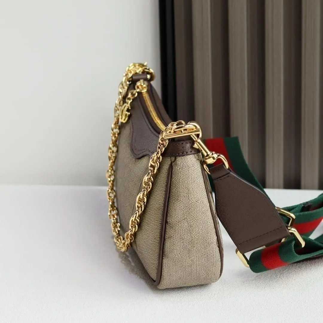 Crescent-shaped single-shoulder bag with leather trim and gold chain, green and red webbing, vintage-inspired everyday underarm bag.
Crescent-shaped single-shoulder bag with leather trim and gold chain, green and red webbing, vintage-inspired everyday underarm bag.
