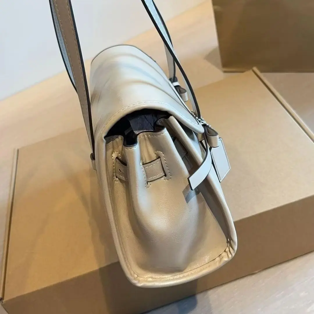 Light grey leather shoulder bag with dual bow details, structured cylindrical shape and top handle.
Light grey leather shoulder bag with dual bow details, structured cylindrical shape and top handle.