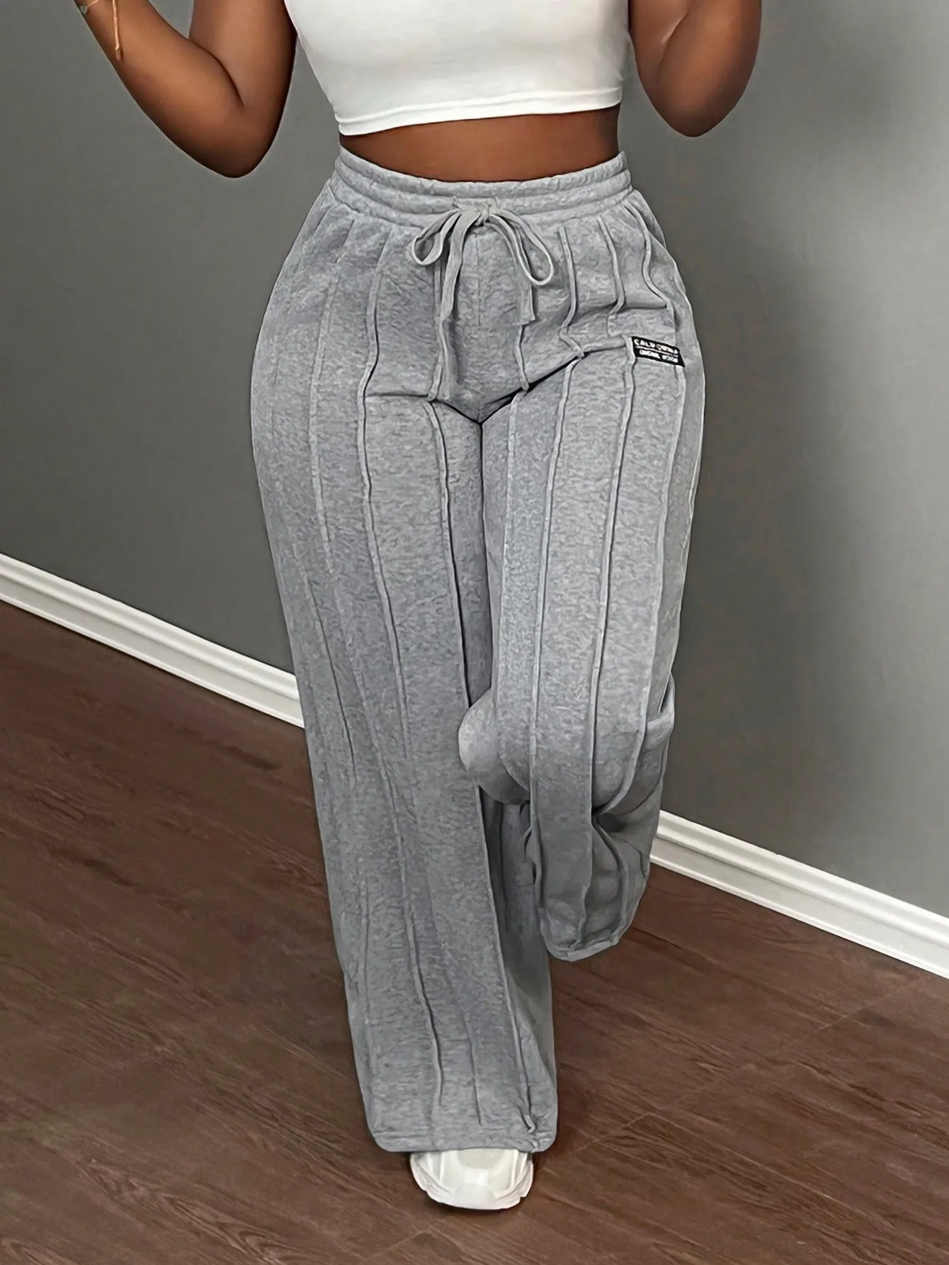 Серые повседневные спортивные брюки с высокой талией, широкими штанинами и завязками на талии
Серые повседневные спортивные брюки с высокой талией, широкими штанинами и завязками на талии