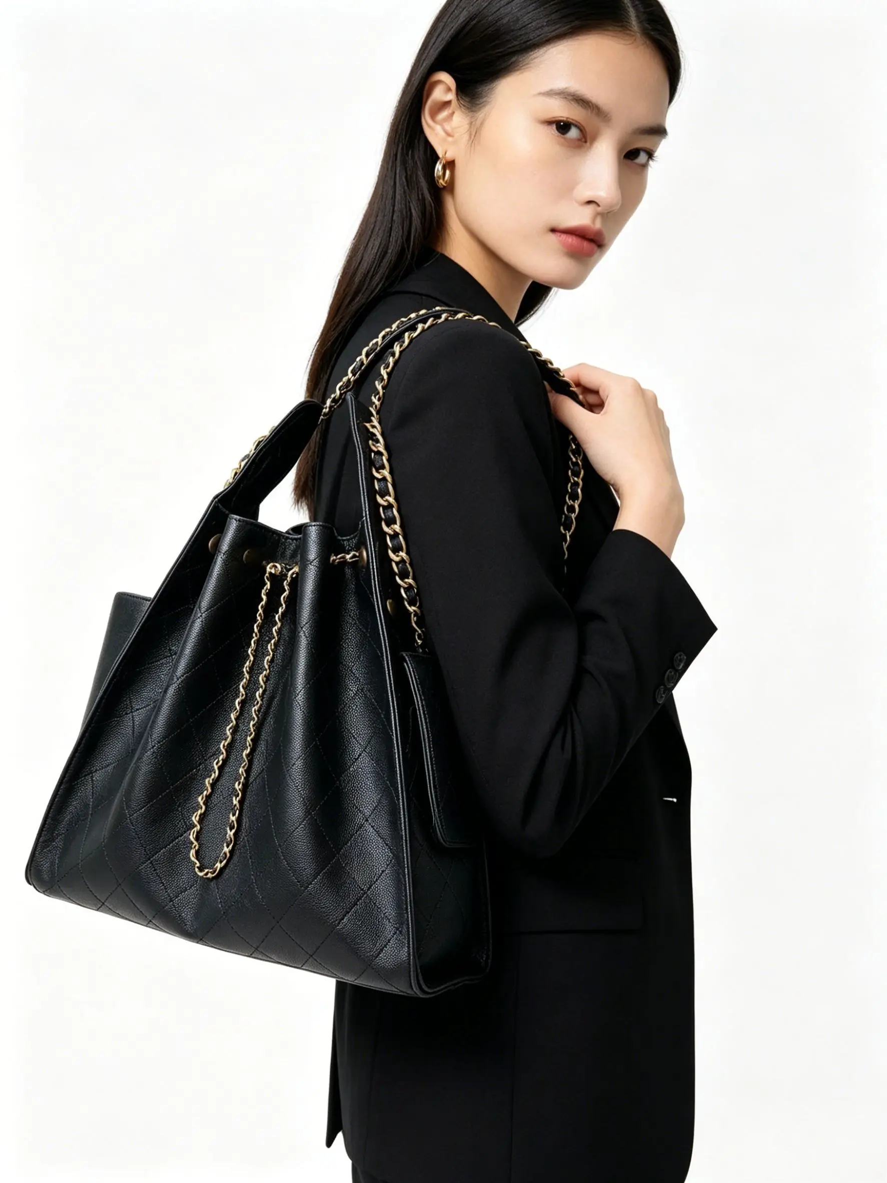 Black quilted leather handbag with gold chain shoulder strap and drawstring closure.
Black quilted leather handbag with gold chain shoulder strap and drawstring closure.