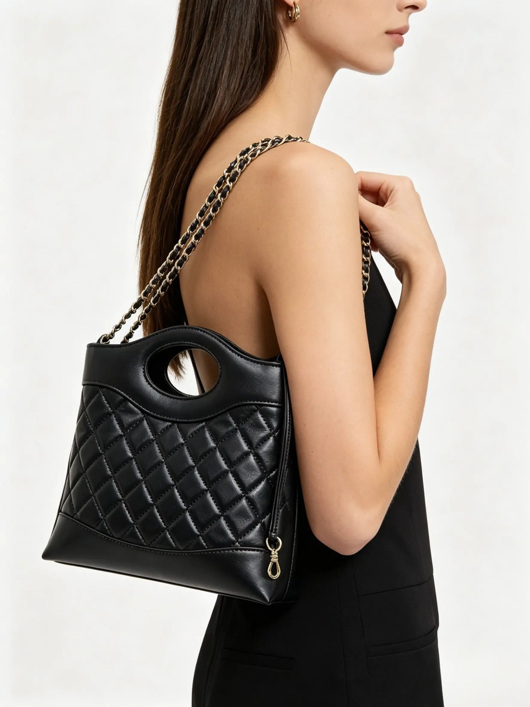 Black quilted leather mini tote bag with cut-out top handle, leather-woven gold-tone chain strap, and diamond stitching.
Black quilted leather mini tote bag with cut-out top handle, leather-woven gold-tone chain strap, and diamond stitching.