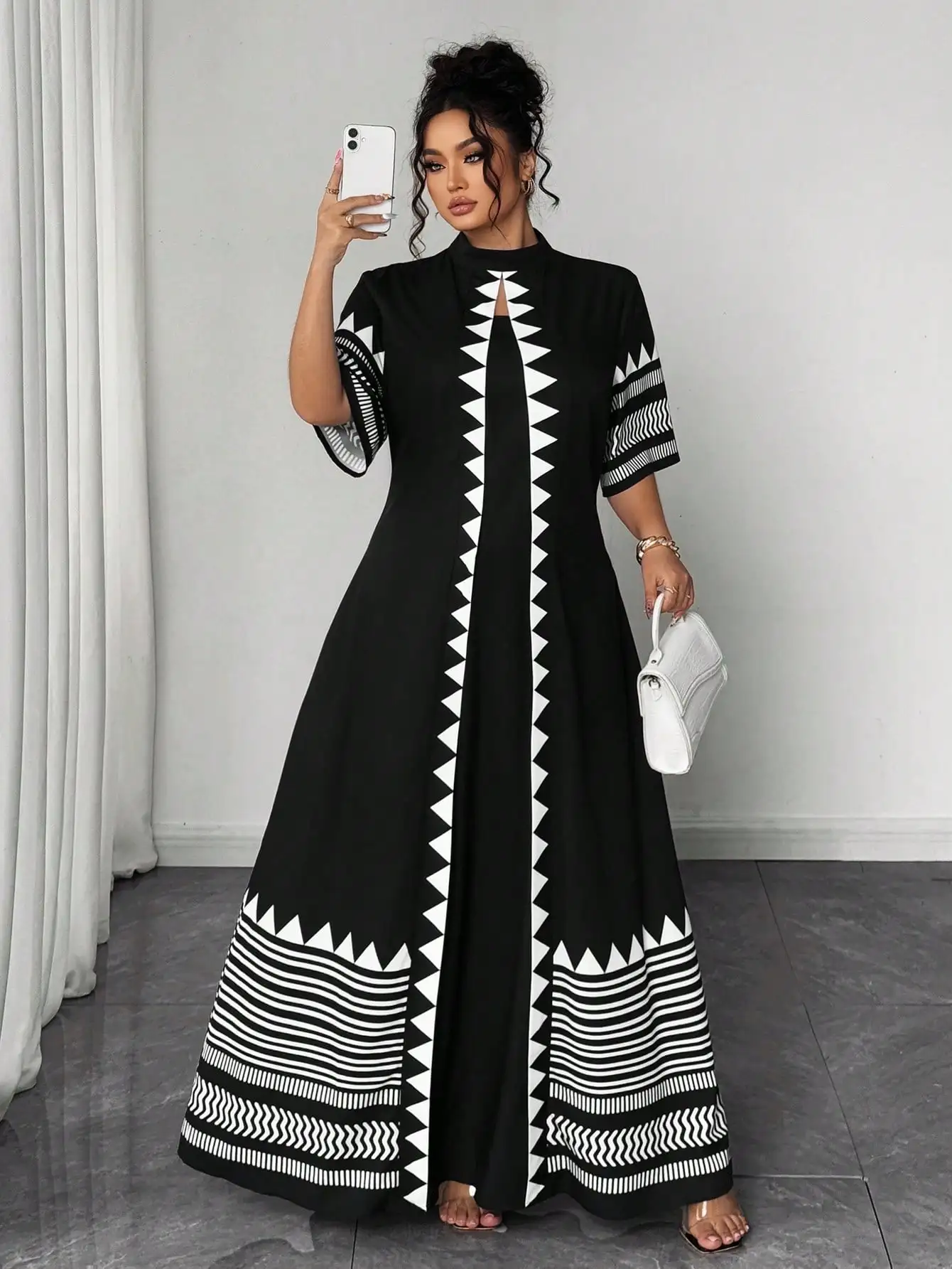 Черно-белое макси-платье с геометрическим принтом, высоким воротником и расклешенными рукавами
Черно-белое макси-платье с геометрическим принтом, высоким воротником и расклешенными рукавами