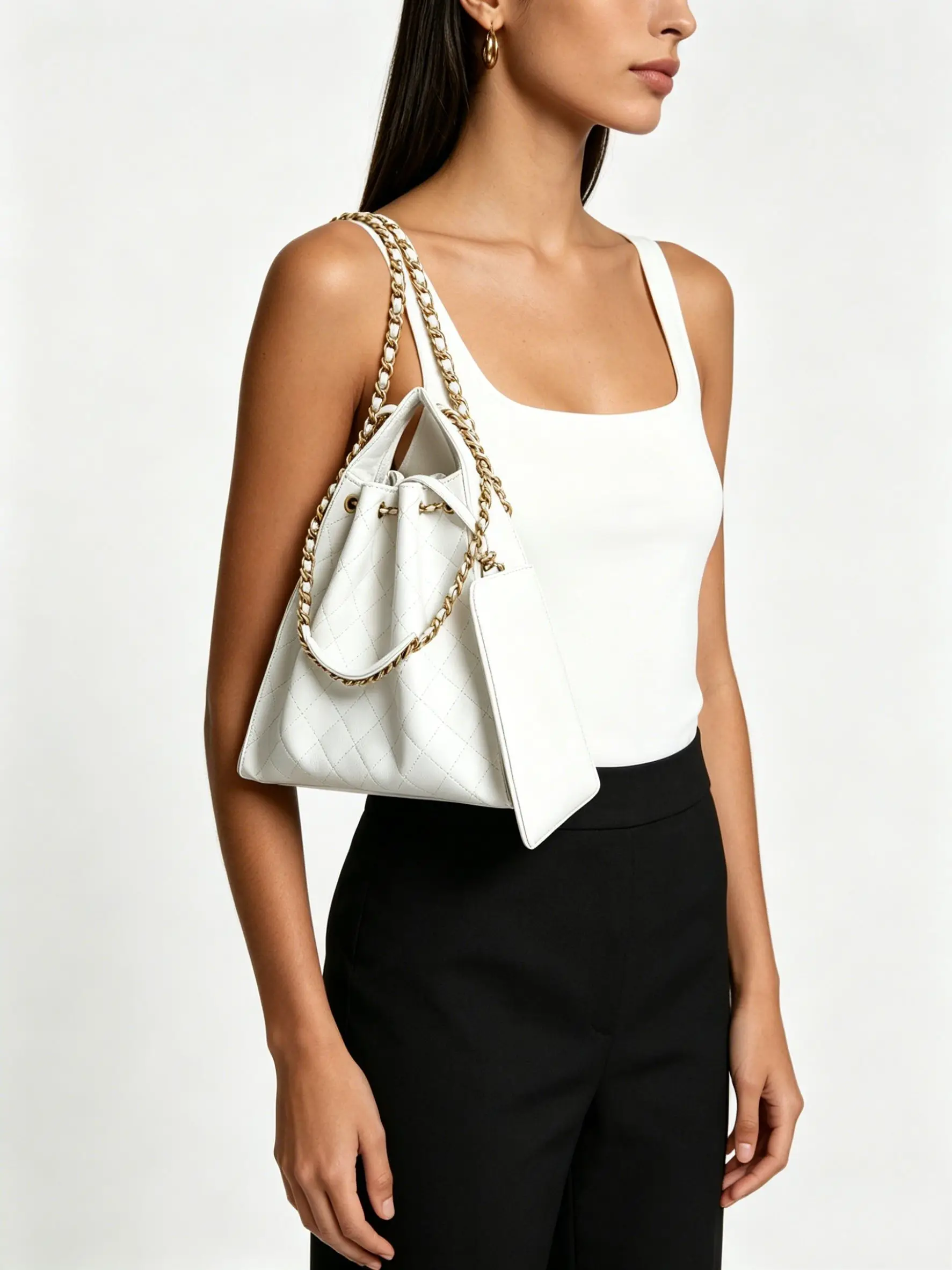 White quilted leather bucket bag with gold-tone chain straps, drawstring closure, and a detachable pouch.
White quilted leather bucket bag with gold-tone chain straps, drawstring closure, and a detachable pouch.