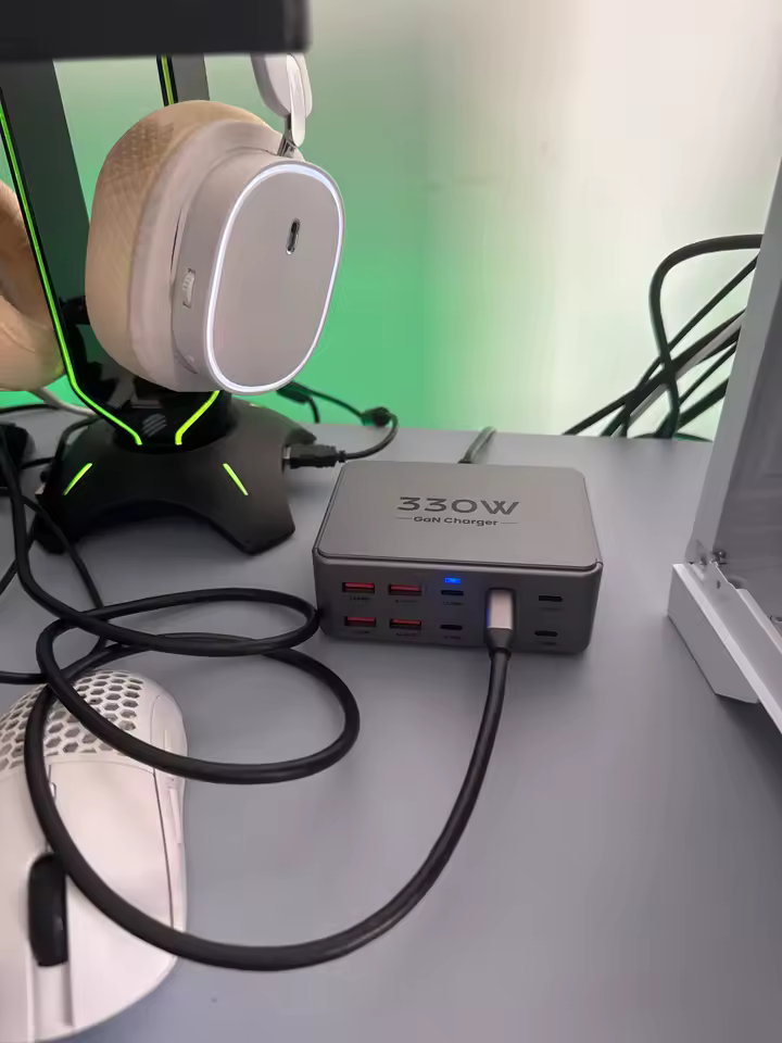 Estação de carregamento TopZero 330W conectada em uma mesa de computador ao lado de fones e mouse
