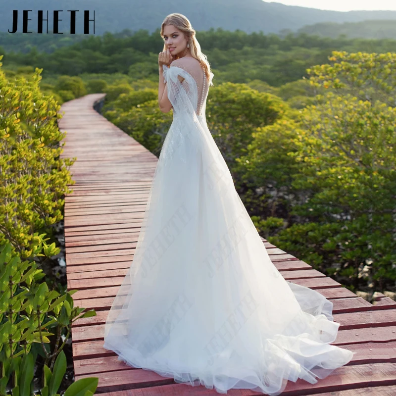 JEHETH O-Neck Cap Mangas Tule Vestidos De Noiva Mulheres Pérola Arco A Linha Vestidos De Casamento Elegant Illusion Backless Vestidos De Novia O-Neck Cap Mangas Tule Vestidos De Noiva Mulheres Pérola Arco A Linha Vesti