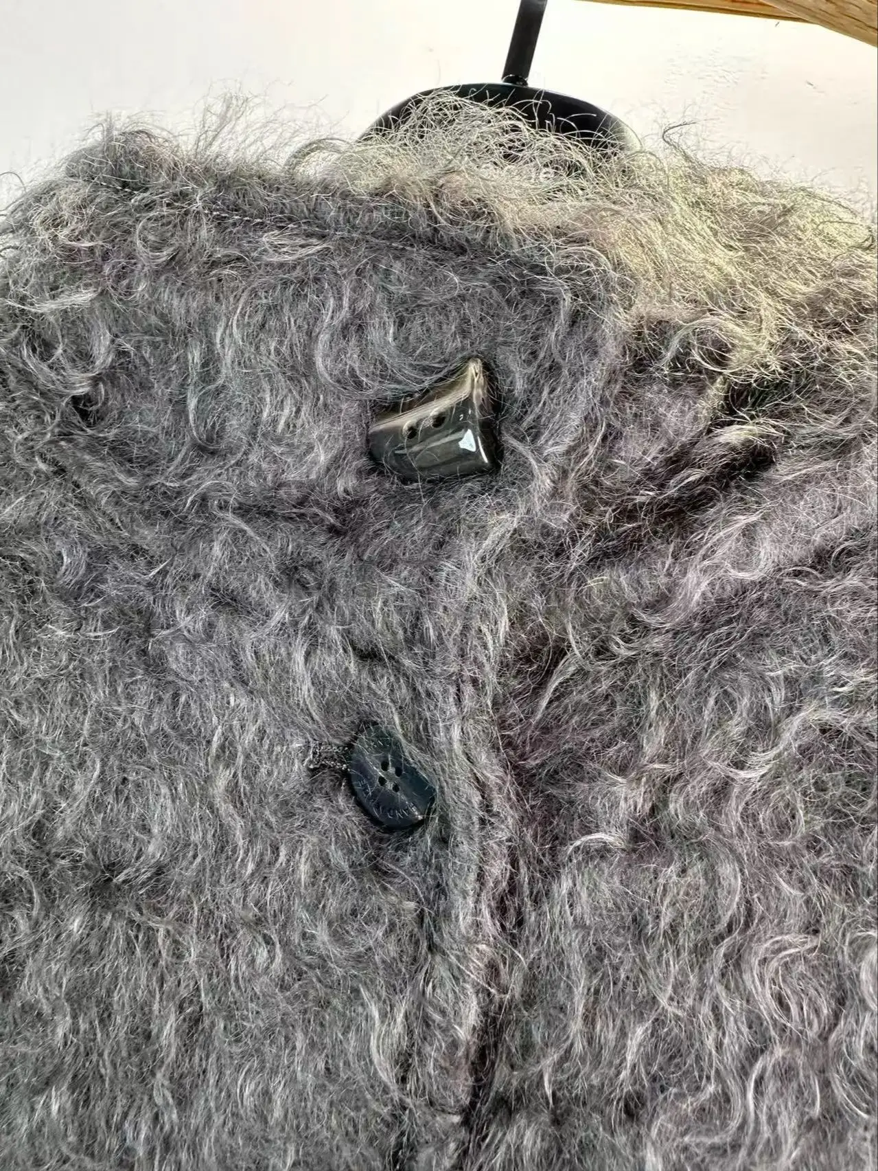 Minimalistyczny zimowy płaszcz damski ze stójką, o średniej długości, wykonany z mieszanki moheru i wełny.