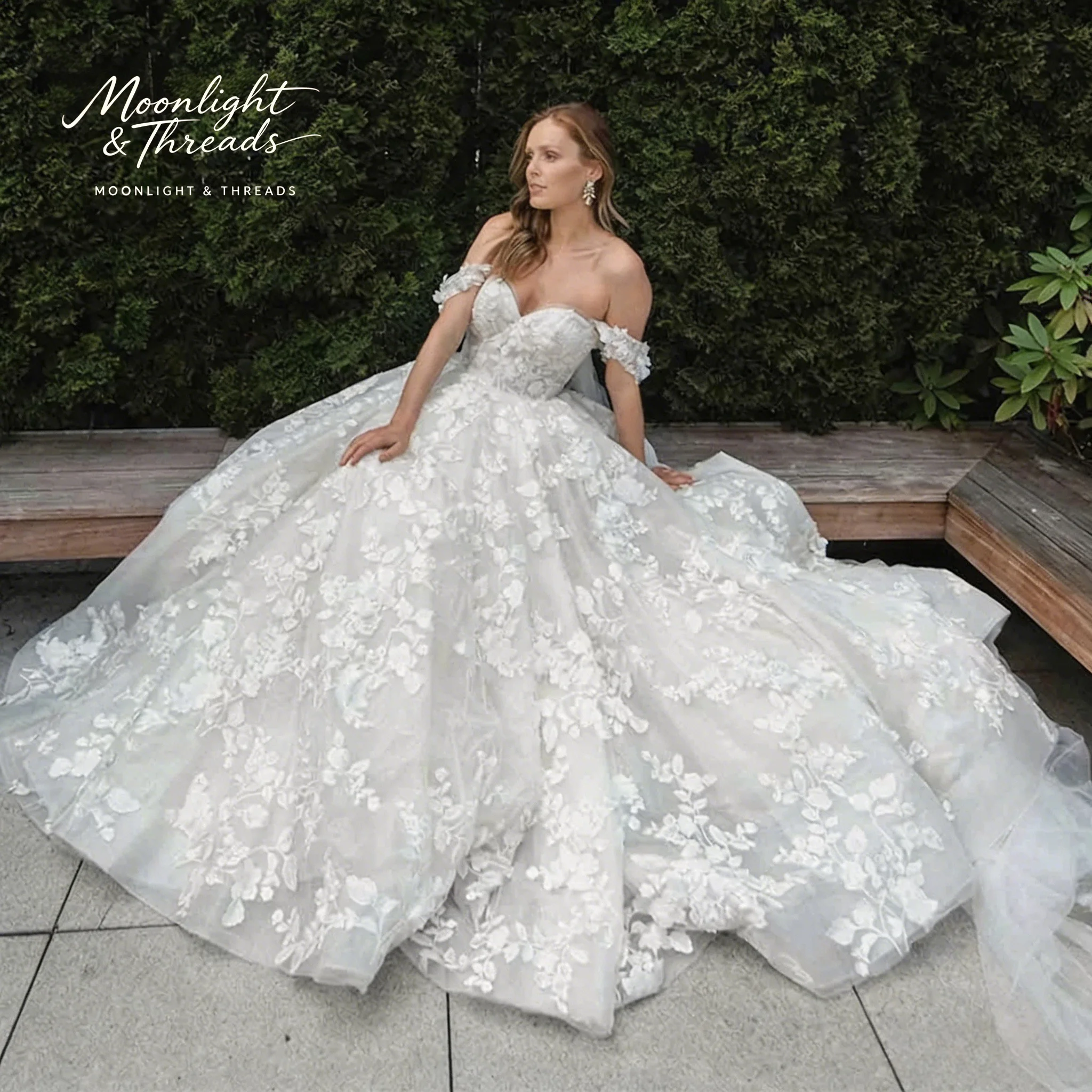 

White off-the-shoulder strapless sleeveless full-skirted formal gown with appliqué embroidery suitable for weddings