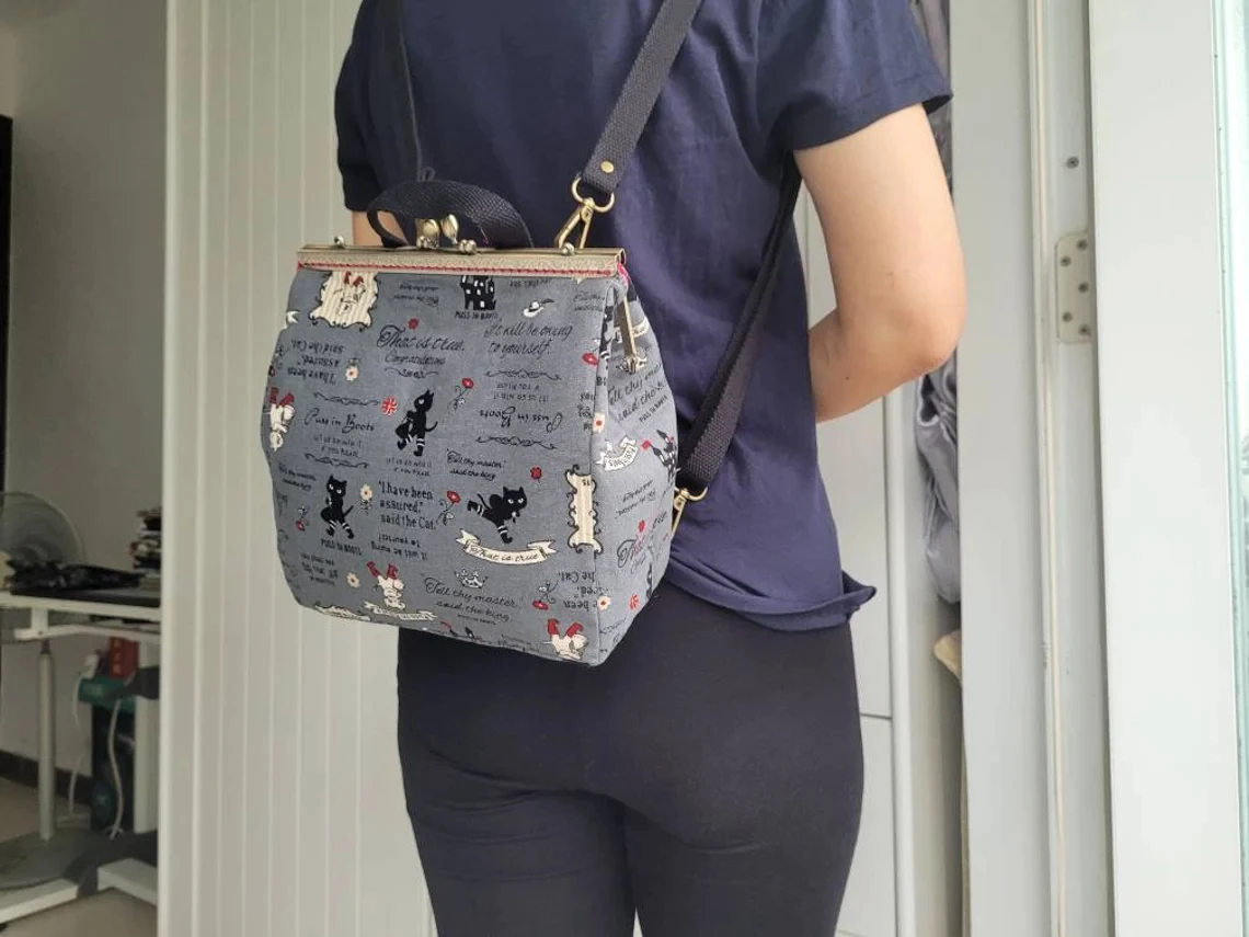 Lost In Vintage Ukuran Besar Puss in Boots Print Kiss Lock Ransel Convertible atau Tas Selempang atau Bahu dengan Logam 23x10x20cm