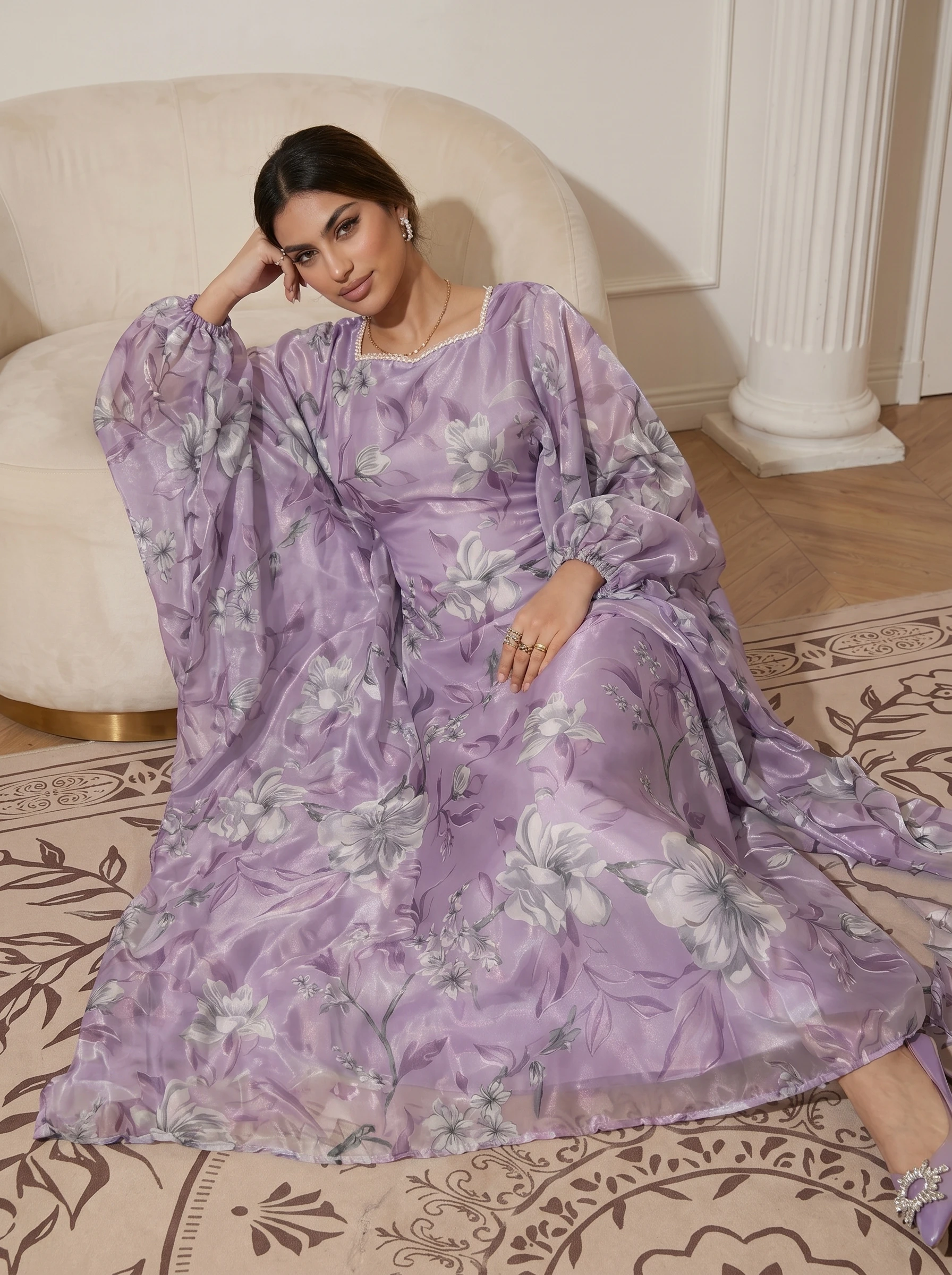 A pale purple floral gown featuring a pearl-embellished neckline and puffed sleeves; an elegant, flowing skirt.