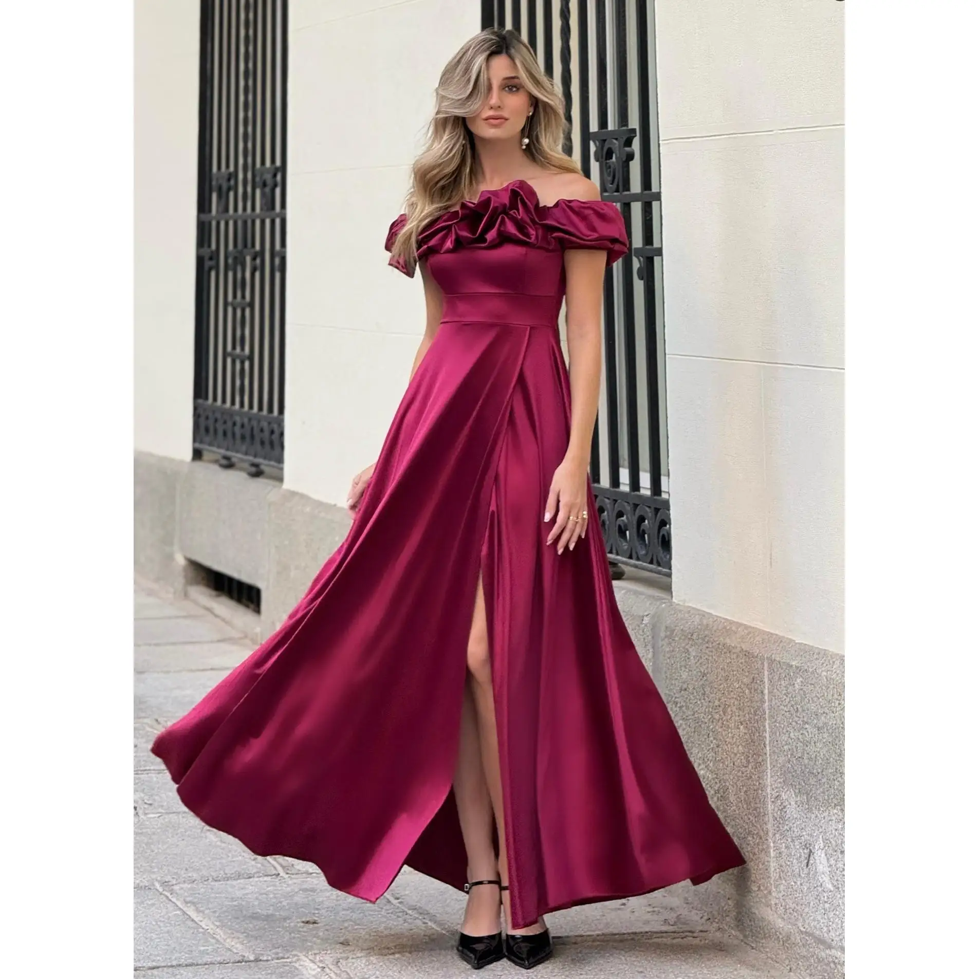 Vestido largo tejido de raso, escote barco. Cremallera trasera invisible con abertura delantera mostrando la pierna, amplia falda con vuelo.