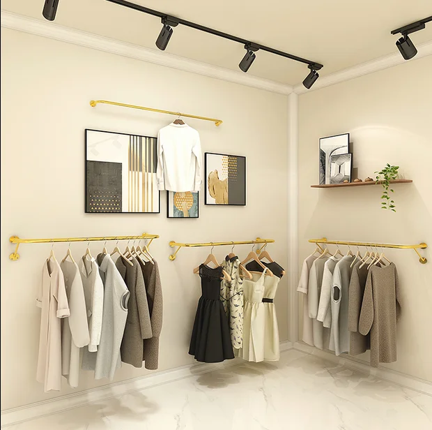 On the wall, hang the clothes shelf of women\'s clothing store, wedding dress, wall shelf, golden clothes hanger.