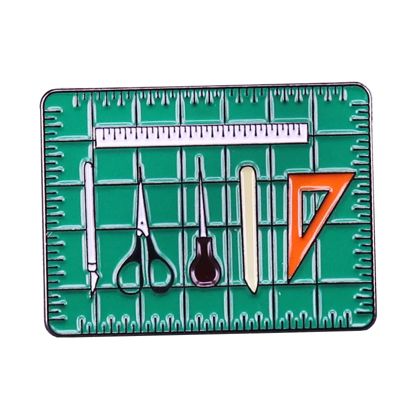 مجموعة أدوات الفنان ، دبوس ، مثلث ، مجلد العظام ، مسطرة awl ، مقص x-acto ، سكين على حصيرة القطع ، بروش ، كتيبات الكتب وقطبية الكتب