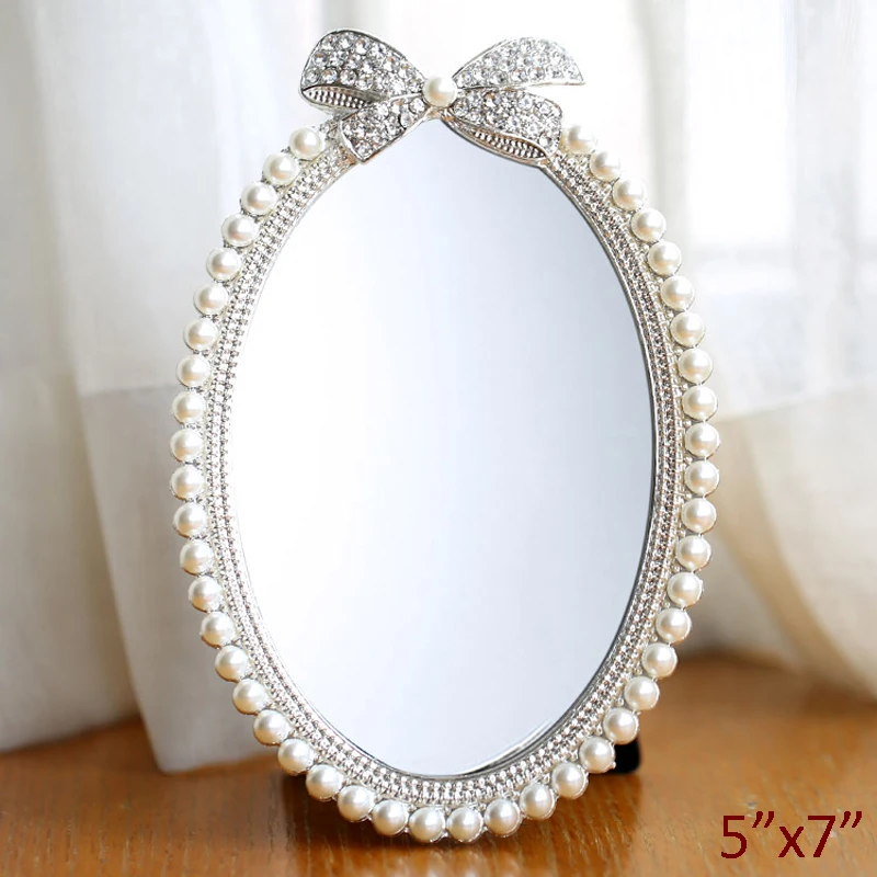 

Shiny Silver Plating with White Pearls and Clear Rhinestones Jeweled Ribbon Design 5x7 inches Oval Metal Framed Tabletop Mirror