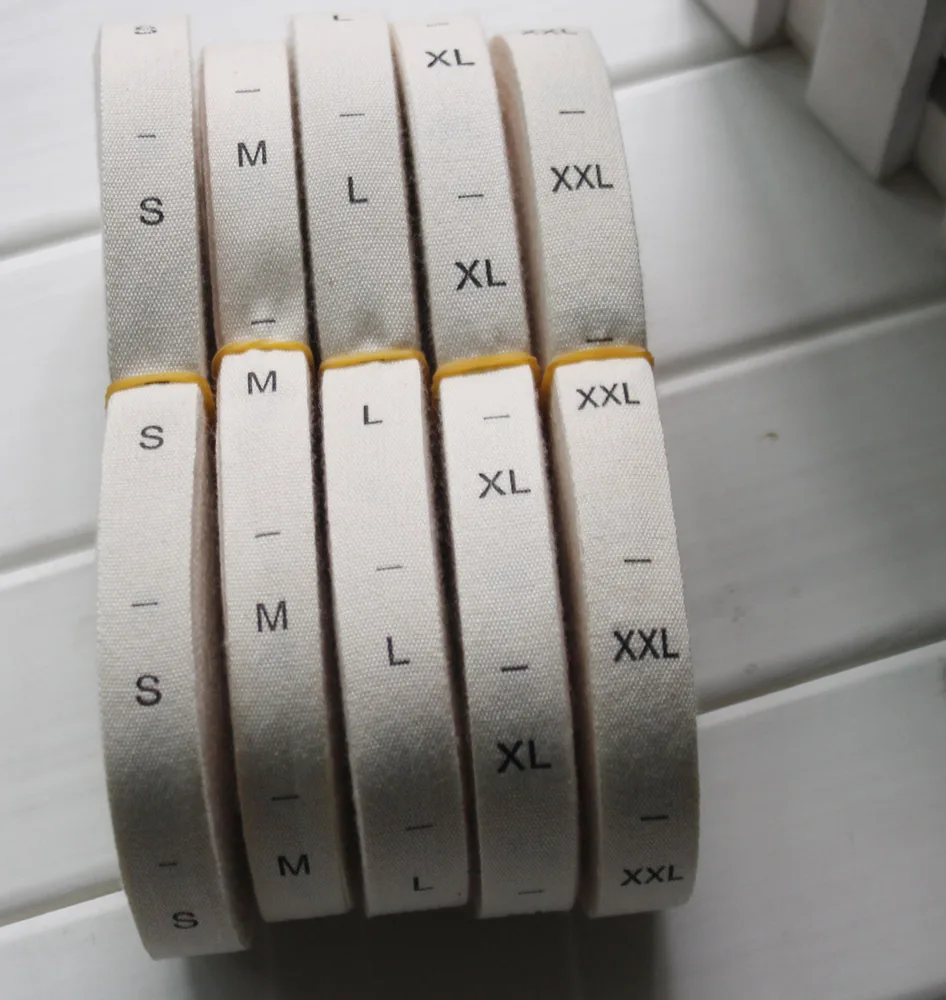 Rollo de existencias 1,2*3,3 cm etiquetas de tamaño estampado de algodón fondo beige natural XS S M L XL XXL 500 piezas / lote