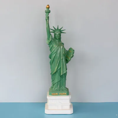 A Statue of liberty sculpture is displayed on living room office book desk as tourist souvenir in New York crafts bookshelf home