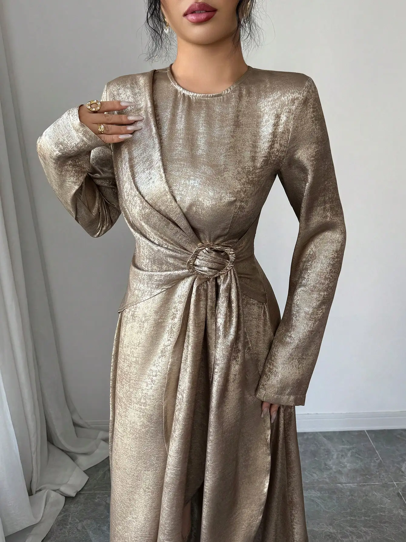 

Элегантное макси-платье из металлизированной ткани с перекрестной завязкой на талии, круглым вырезом, длинными рукавами и А-образным силуэтом