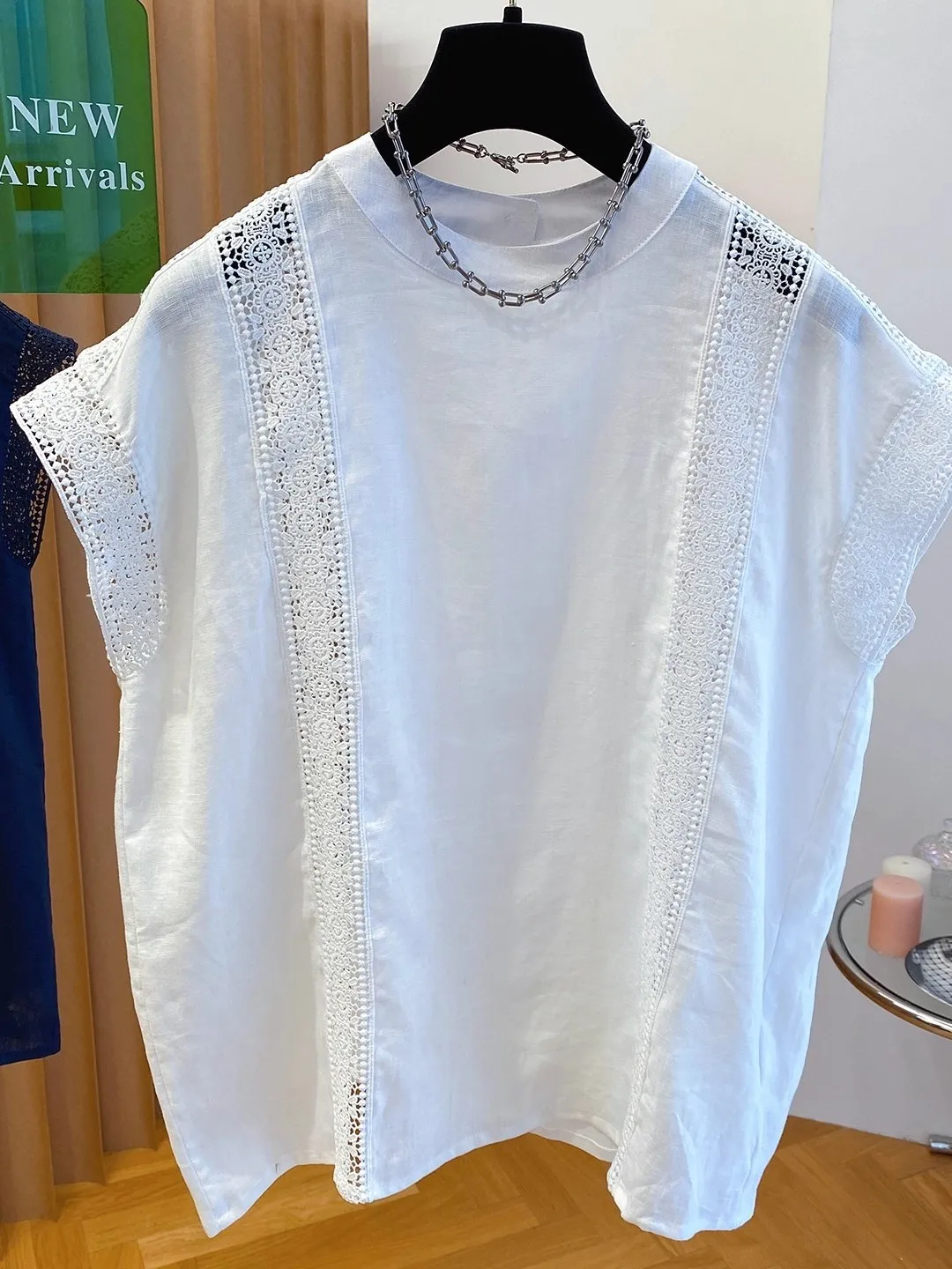 Letnia, codzienna bluzka damska z bawełny i lnu, z ażurowym wzorem kwiatowym, luźny krój, okrągły dekolt, biała, z falbankami.