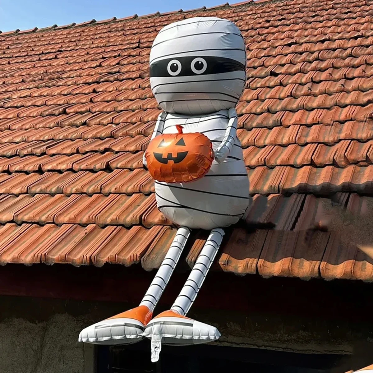 مومياء تحمل بالون من رقائق الألومنيوم اليقطين باللون الأبيض والبرتقالي لعناصر رعب لتزيين حفلات الهالوين