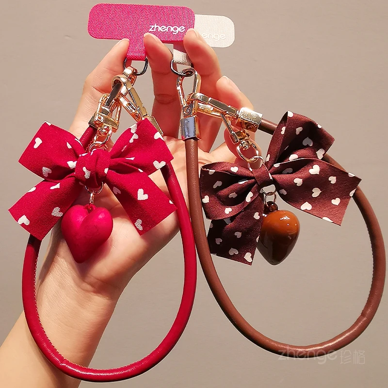 

‌2026 New Women's Leather Phone Lanyard: Bowknot Heart Pendant, Anti-Lost Wrist Strap, Universal Fit