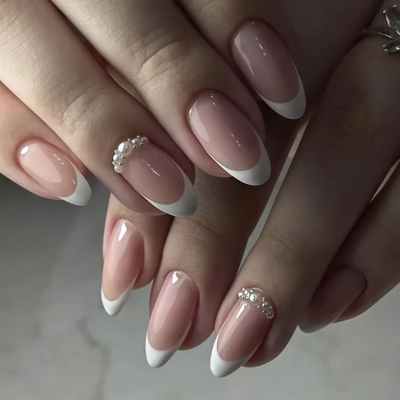 24 faux ongles élégants en forme d'amande, ornés de perles et de strass, effet gaufré, couleur nude et blanc, style français classique, pointus, brillants et neutres.
