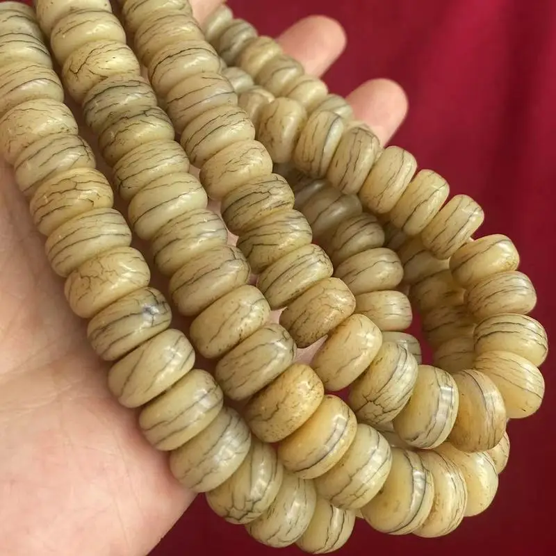 Tibetan- antique-style and distressed cow bone beads with a textured pill-like design forming a single-strand long bra