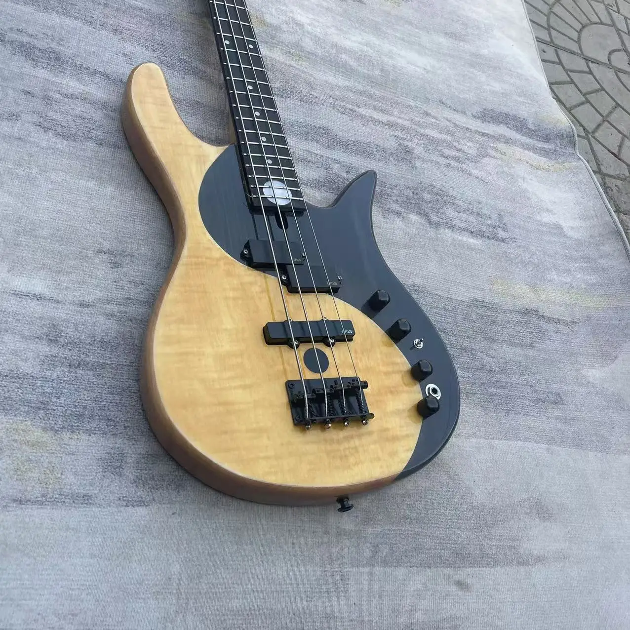 Electric bass 4 chord yin-yang butterfly style electric bass, with a natural wood color body and black accessories. Factory phot