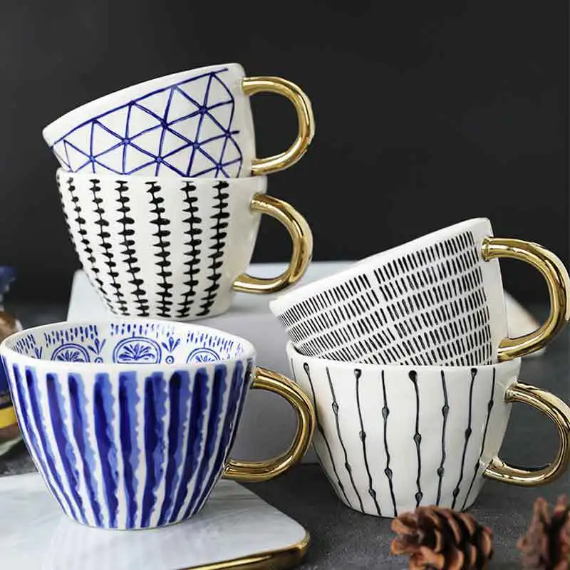 

The export hand holds an irregular wide mouth ceramic cup, geometric gold handle coffee cup,