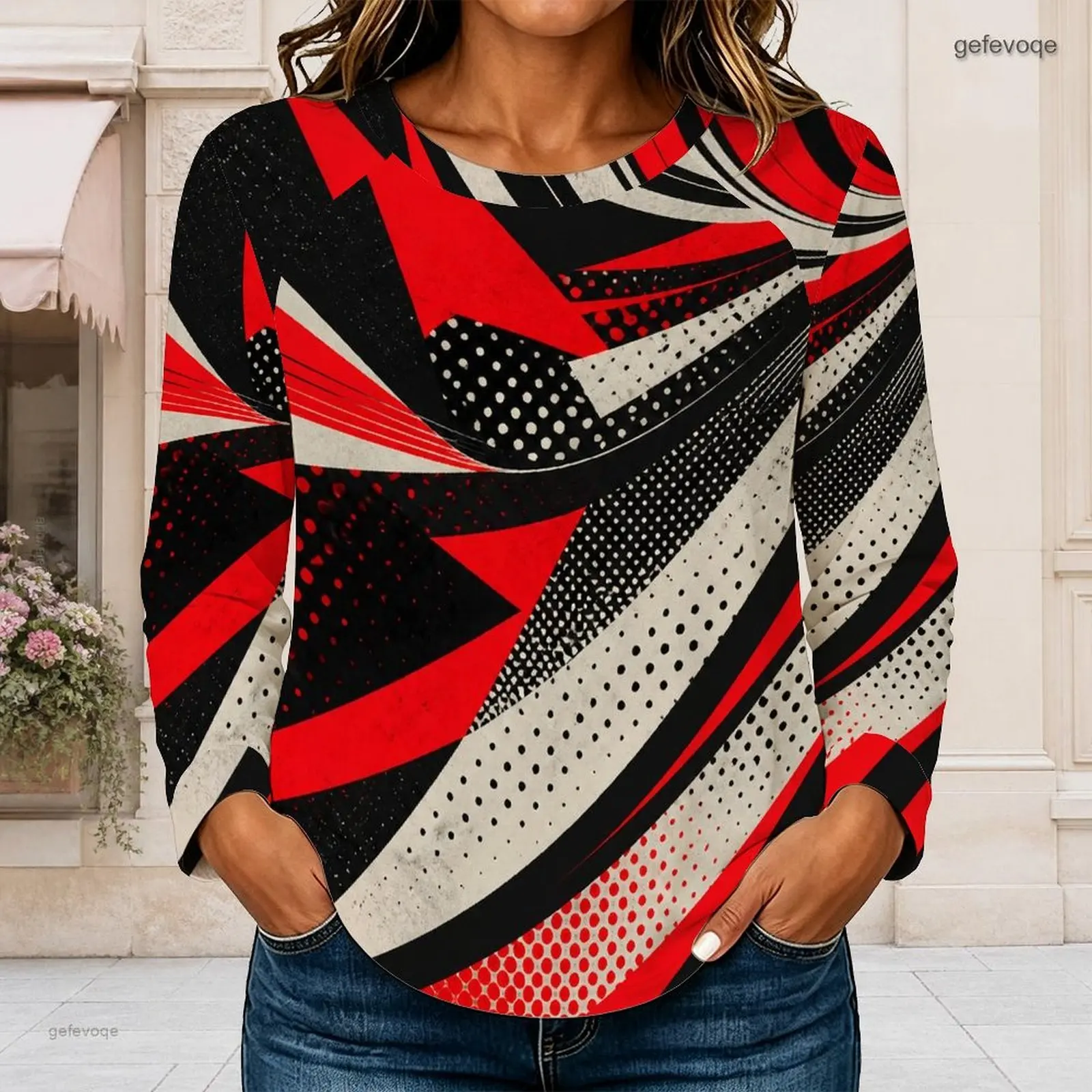 Blusa de manga larga con cuello redondo, estampado geométrico de lunares en rojo, negro y blanco, con bajo curvo.