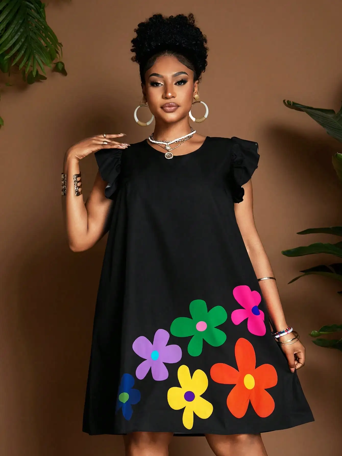 

Черное платье А-силуэта с красочными цветочными аппликациями, рукавами-крылышками с рюшами и круглым вырезом.