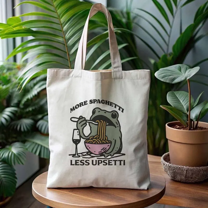 A tote bag with a cartoon pattern of a frog eating noodles，Lightweight and reusable canvas shoulder bag，Suitable for school、Trav