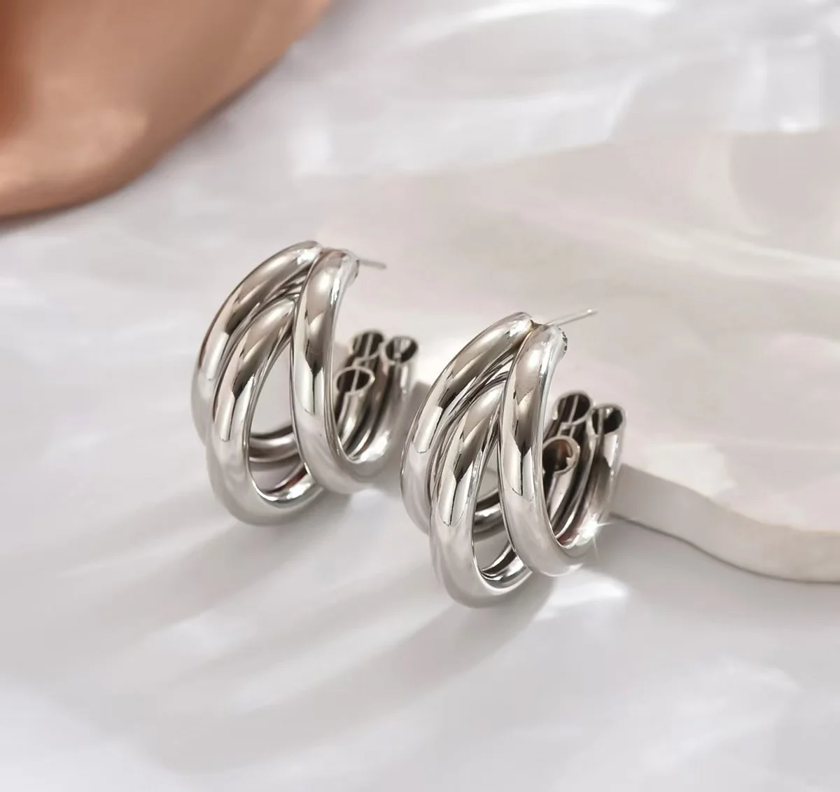 أقراط دائرية ذهبية للسيدات، مصنوعة من مادة معدنية، تتميز بتصميم هندسي أنيق وعجلي، مما يزيد عن كبيرة وفاخرة